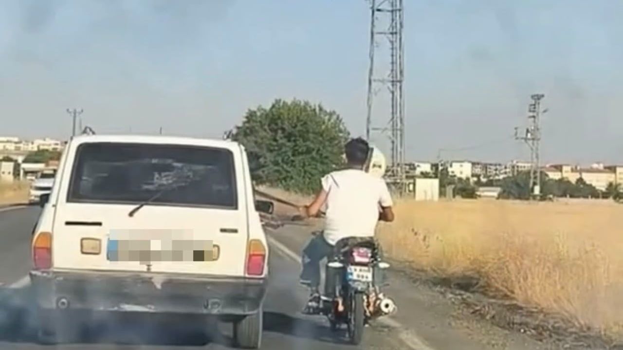 Otoyolda tehlikeli manevra: motosiklet otomobilin emniyet kemerine tutunarak ilerledi