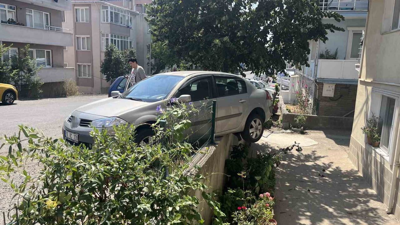 El frenini çekmeyi unutan sürücünün otomobili bahçe duvarında asılı kaldı