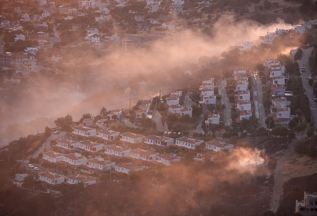 İzmir'in Dikili ilçesinde ormanlık alanda başlayan ve yerleşim yerlerine yaklaşan yangına havadan...