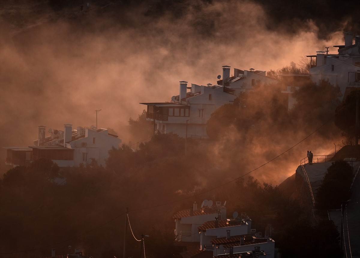 İzmir'in Dikili ilçesinde ormanlık alanda başlayan ve yerleşim yerlerine yaklaşan yangına havadan...
