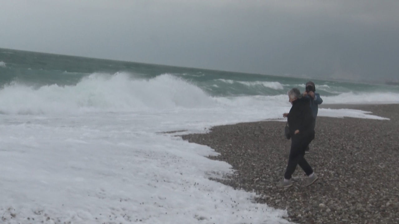 ANTALYA’DA ETKİLİ OLAN FIRTINALI HAVAYA RAĞMEN SAHİLE AKIN EDEN ANTALYALILAR, DALGALARIN...