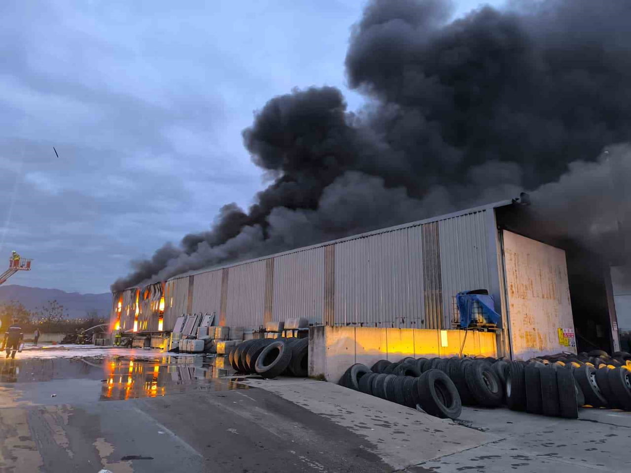 HATAY’DA ALEVLERE TESLİM OLAN ULTRANS LOJİSTİĞE AİT LASTİK DEPOSUNDAKİ YANGINA İTFAİYE EKİPLERİNİN...