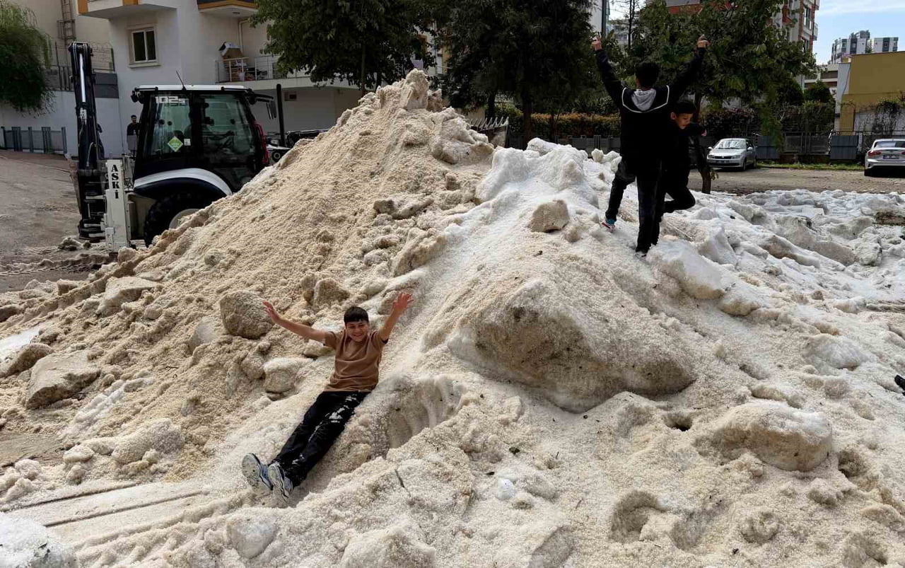 ADANA'DA DÜN ETKİLİ OLAN DOLU YAĞIŞININ ARDINDAN OLUŞAN VE ERİMEYEN BUZ KÜTLELERİNDE ÇOCUKLAR KAR...
