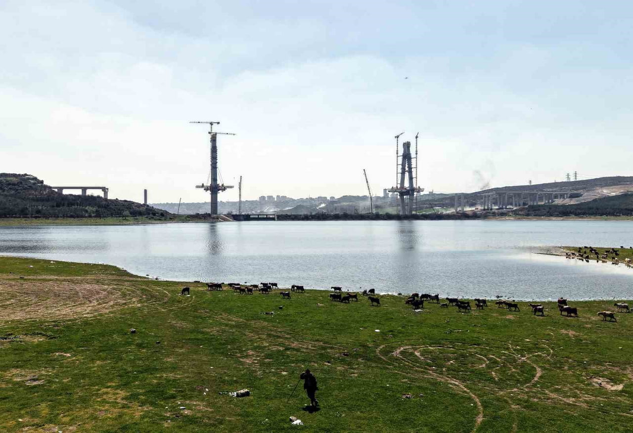 SAZLIDERE KÖPRÜSÜ HIZLA YÜKSELİRKEN, HEMEN YANI BAŞINDA KEÇİLERİN ÇOBAN EŞLİĞİNDE MERADA OTLAMAYA...