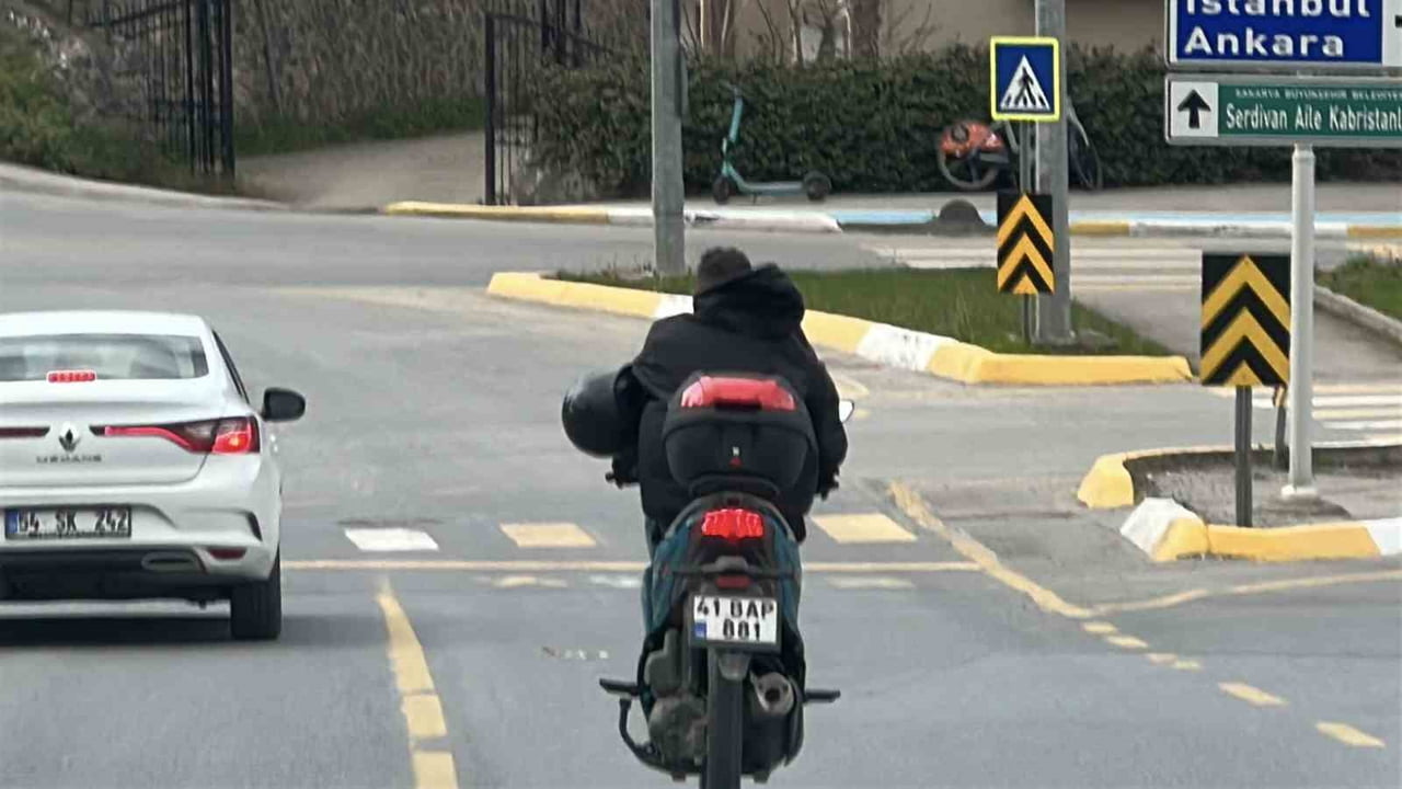 SERDİVAN İLÇESİNDE MOTOSİKLET SÜRÜCÜSÜNÜN KASKINI TAKMAK YERİNE KOLUNA GEÇİREREK TRAFİKTE...