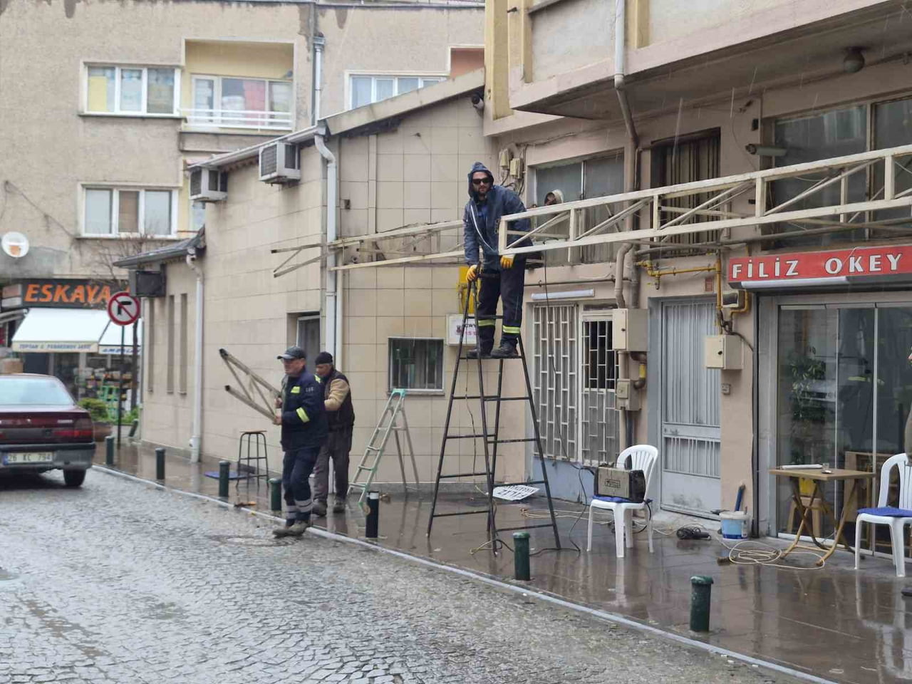 VATANDAŞLAR YAĞMURDAN KAÇACAK YER ARARKEN, BİR DÜKKANIN TENTESİNİ ONARMAYA ÇALIŞAN VATANDAŞIN...