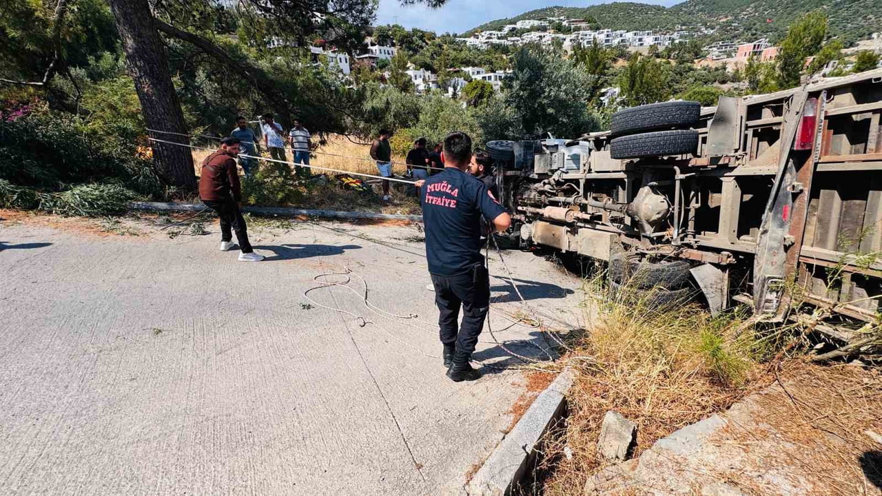 MUĞLA’NIN BODRUM İLÇESİNDE İŞ MAKİNESİ TAŞIYAN KAMYONUN YOKUŞ ÇIKTIĞI SIRADA DEVRİLİRKEN, KAZADA...