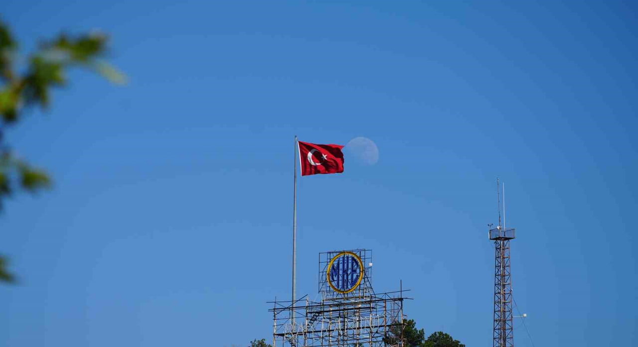 KIRIKKALE'DE GÜN İÇİNDE BELİREN ŞİŞKİN AY, MAVİ GÖKYÜZÜNDE DALGALANAN TÜRK BAYRAĞIYLA AYNI KAREDE...