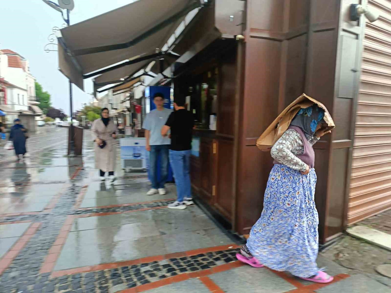YAĞMURA HAZIRLIKSIZ YAKALANAN VATANDAŞLAR ISLANMAMAK İÇİN İŞYERLERİ ÖNLERİNDE TENTE ALTINDA...