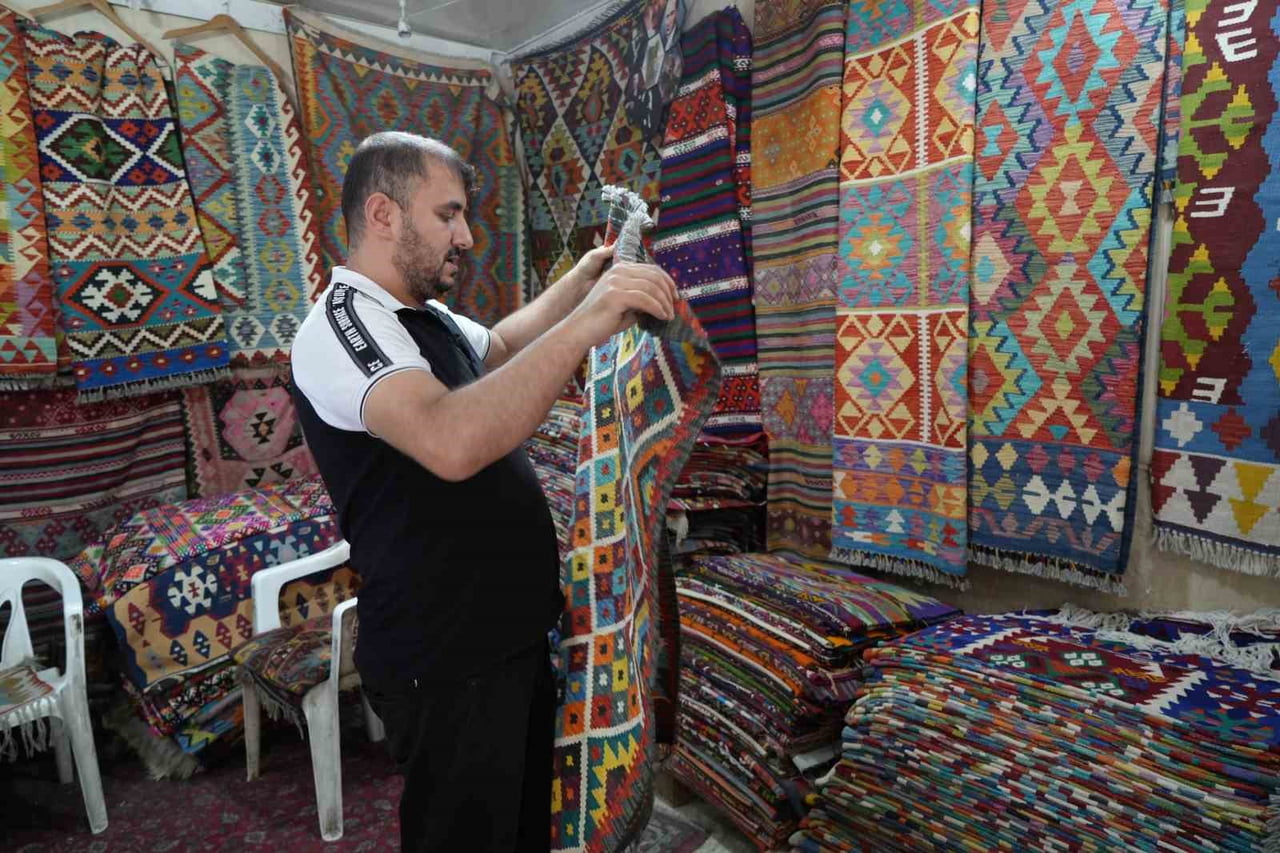 YÖRÜK KÖYLERİNDEN TOPLADIĞI HALI VE KİLİMLERİ SATARAK GEÇMİŞİ GELECEĞE TAŞIYOR