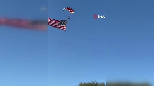 ABD’nin California eyaletinde ABD bayrağı ile gösteri yapan paraşütçü inişe geçtiği sırada tribüne...