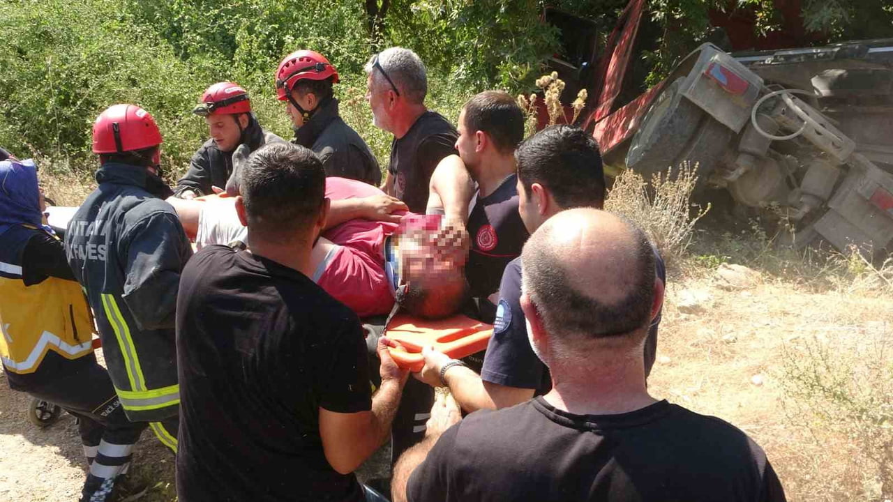 ANTALYA’NIN MANAVGAT İLÇESİNDE DORSESİNDE KUM YÜKLÜ ÇEKİCİ YAN YATARAK YOL KENARINDA BULUNAN DERE...