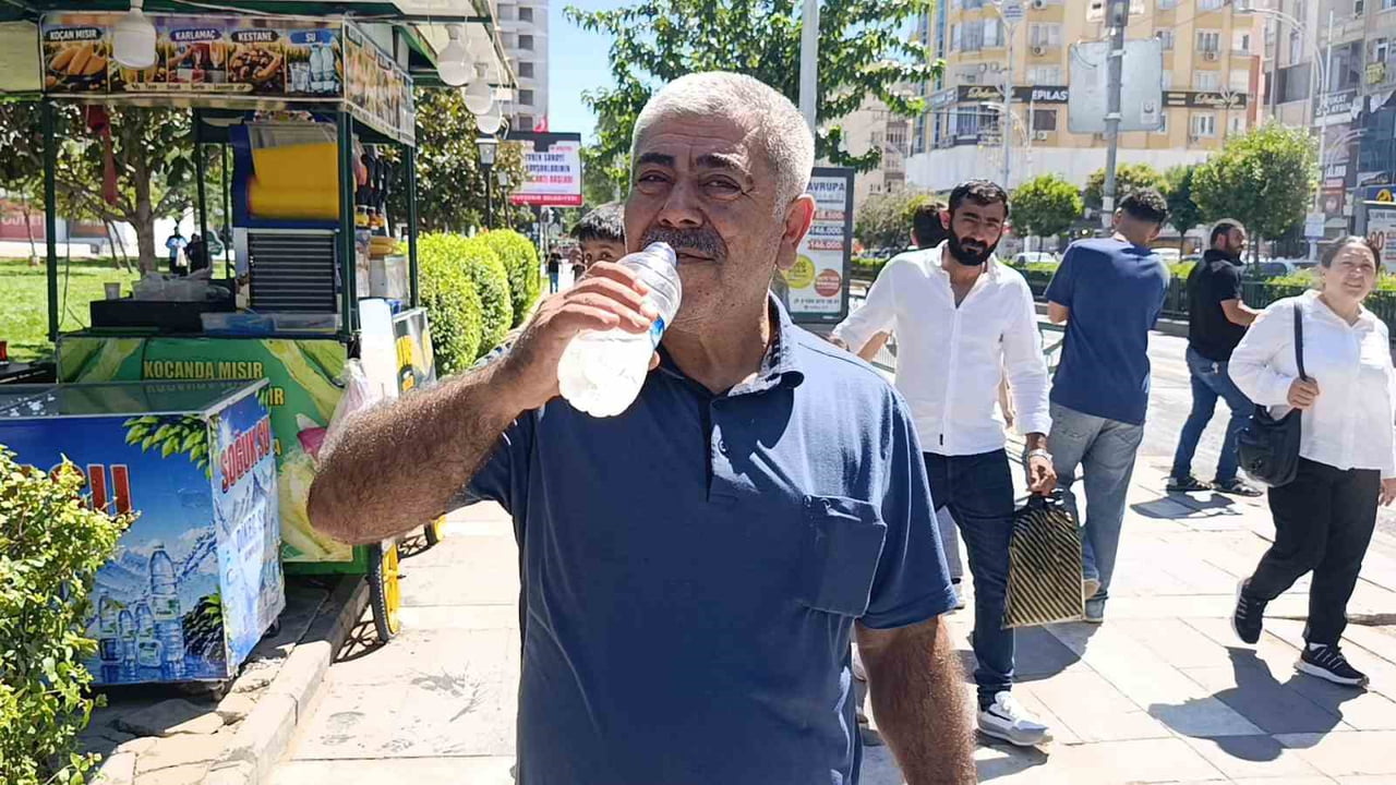 BAZI VATANDAŞLARIN SU İÇEREK, BAZISININ DA ŞAPKA KULLANARAK SICAKLARDAN KORUNMAYA ÇALIŞTIĞI...