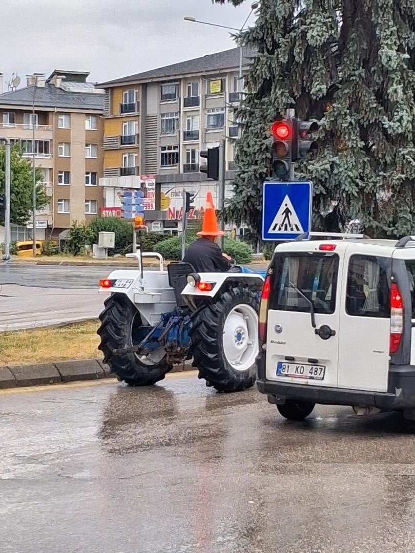 BOLU’DA SAĞANAK SIRASINDA YAĞMURDAN KORUNMAK İSTEYEN TRAKTÖR SÜRÜCÜSÜ, BAŞINA TRAFİK DUBASI...