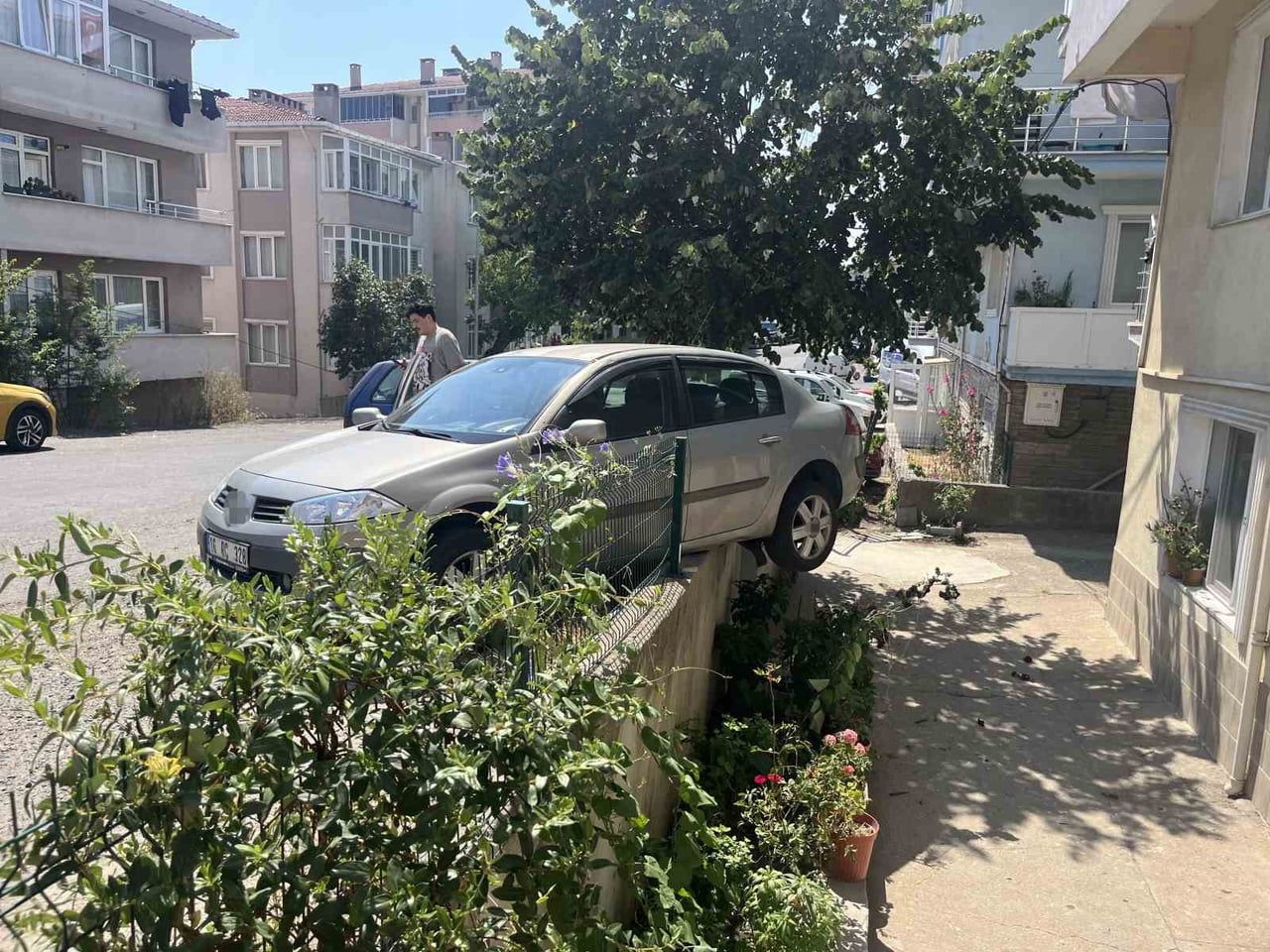 EL FRENİ ÇEKİLMEYİ UNUTULAN OTOMOBİL, BAHÇE DUVARINDA ASILI KALDI: O ANLAR KAMERADA