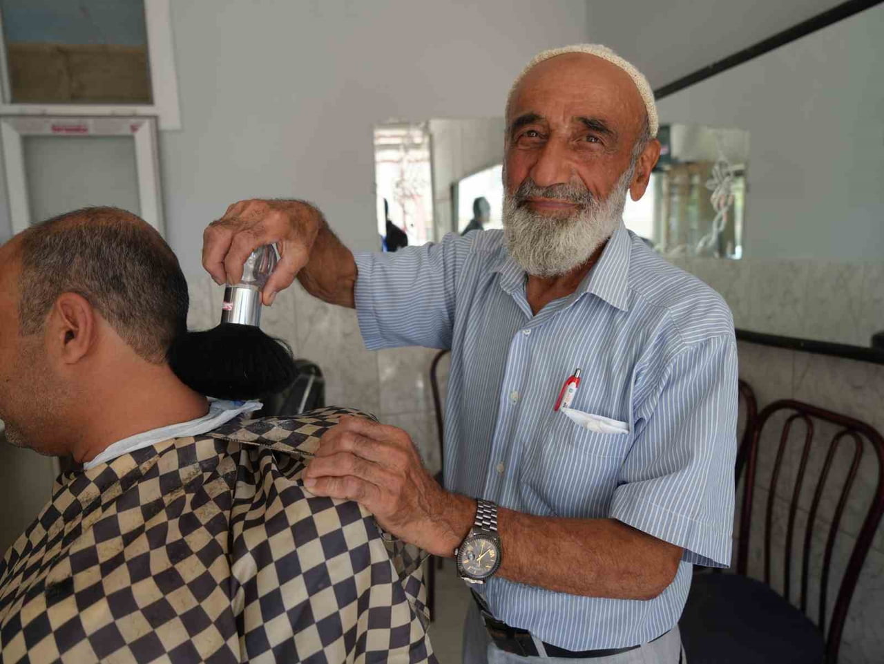 ABDULKADİR AKSOY, 65 YILDIR BERBERLİK MESLEĞİNİ SÜRDÜREREK MÜŞTERİLERİNİ TIRAŞ EDİYOR.